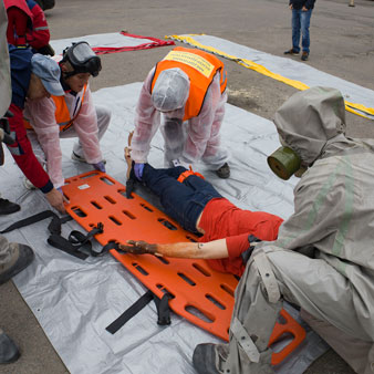 Grupo de personas con equipos de protección realiza un simulacro de rescate con una camilla